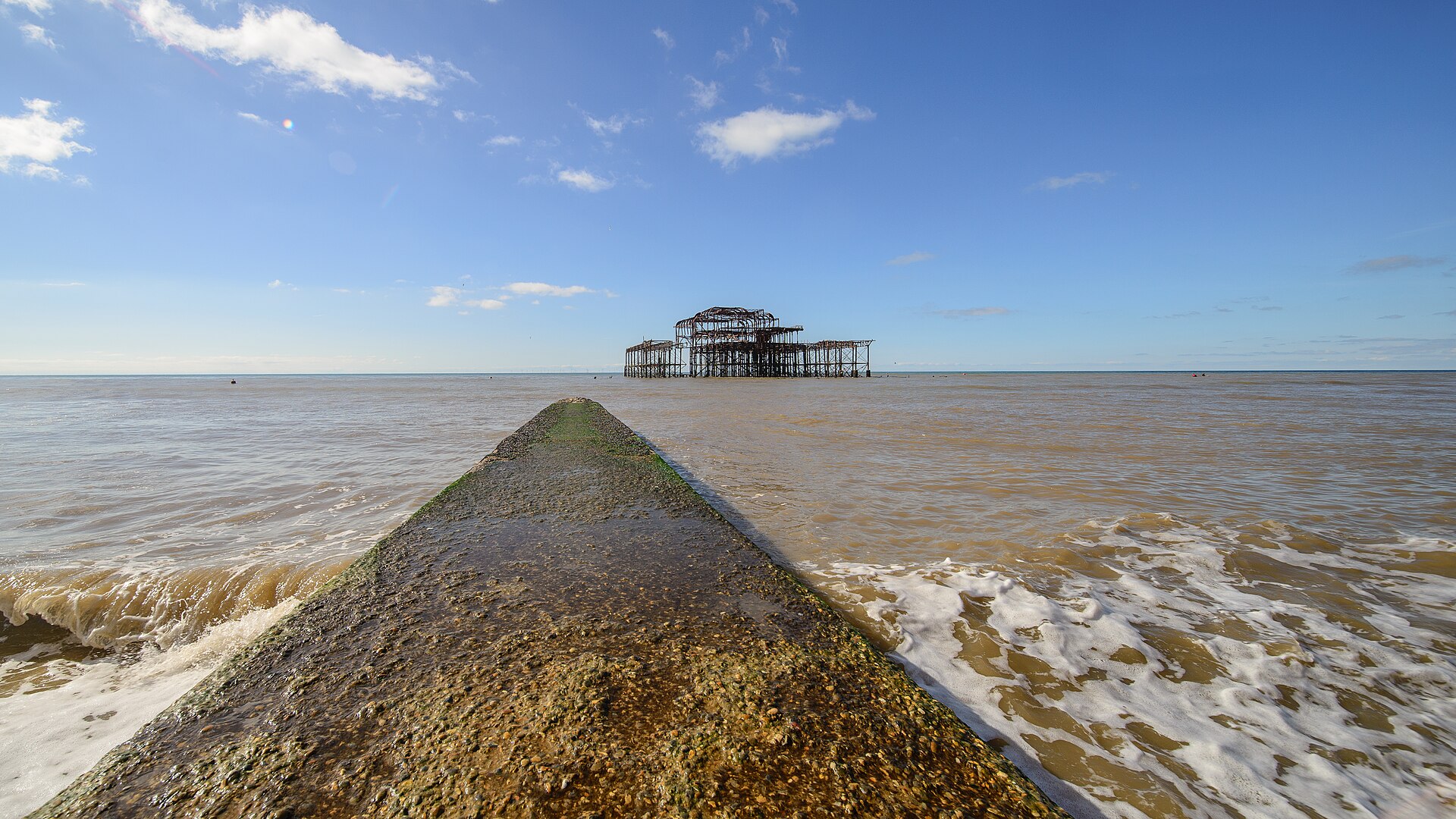 Groyne leading the eye out to the West Pier ruin, blue sky