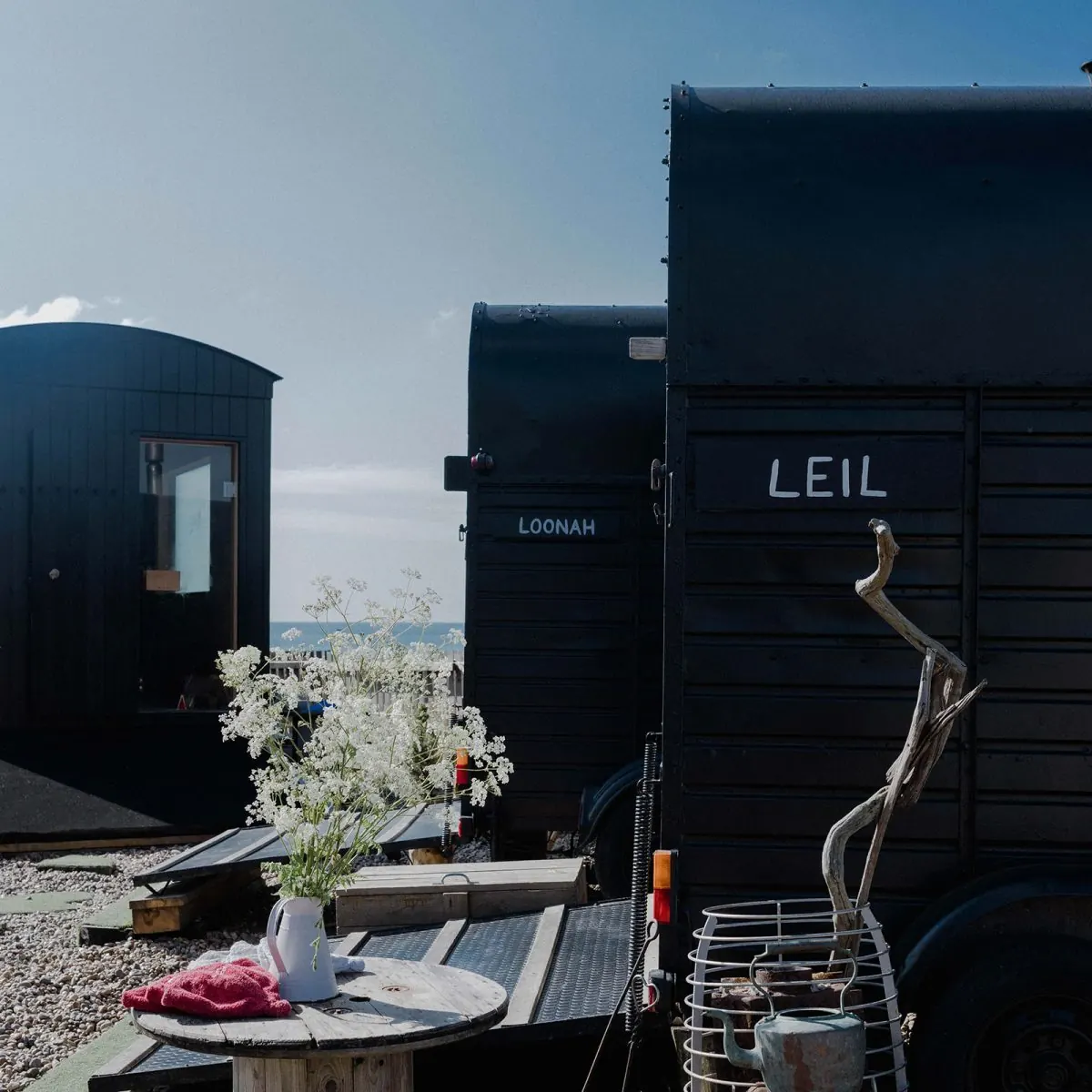 Black sauna huts on the shingle with the sea behind