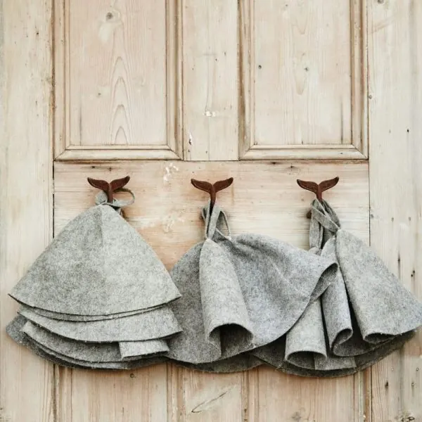 Felt sauna hats hanging on a wooden door
