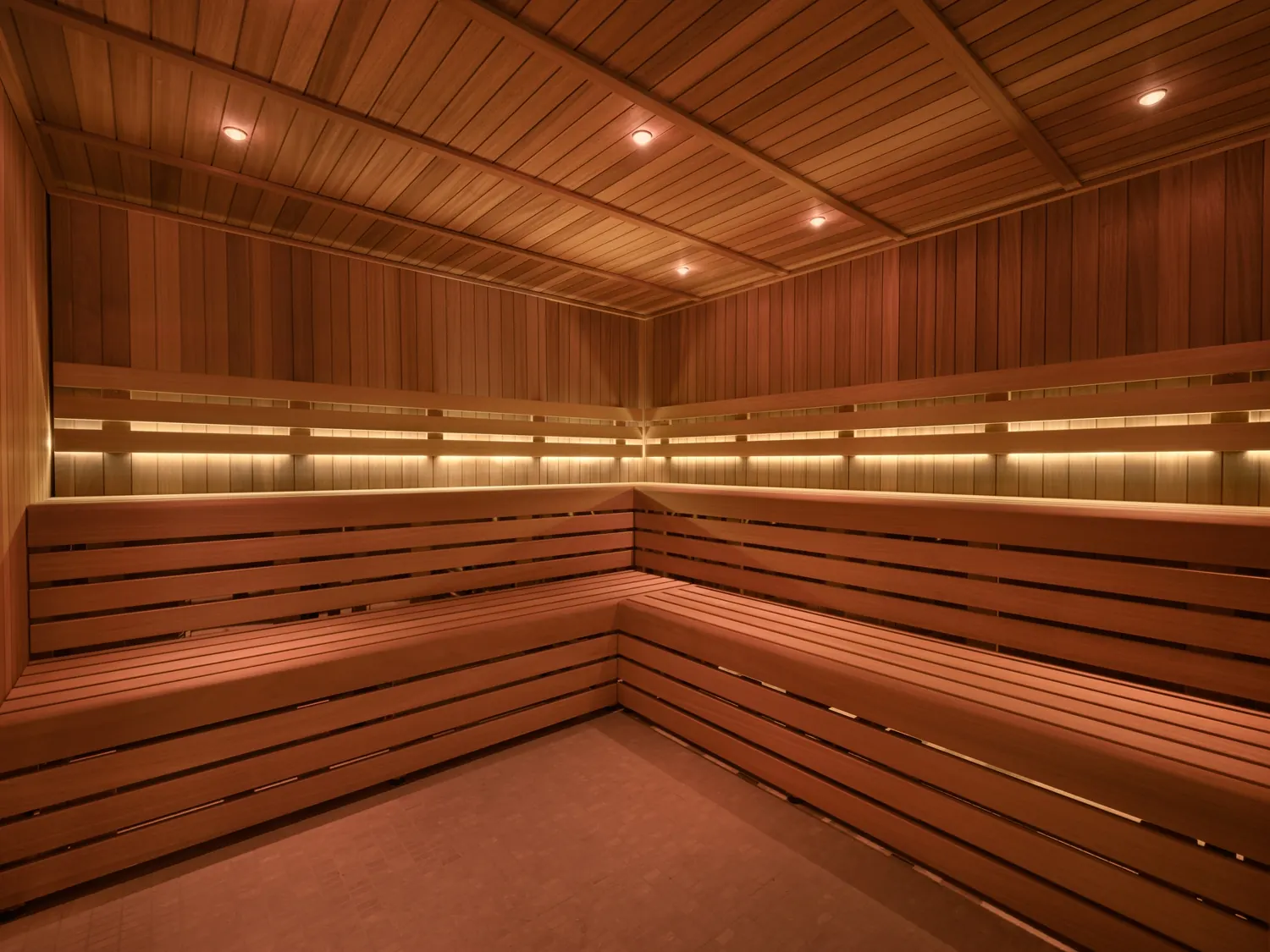 Empty wooden sauna with tiered L-shaped benches and warm ambient lighting