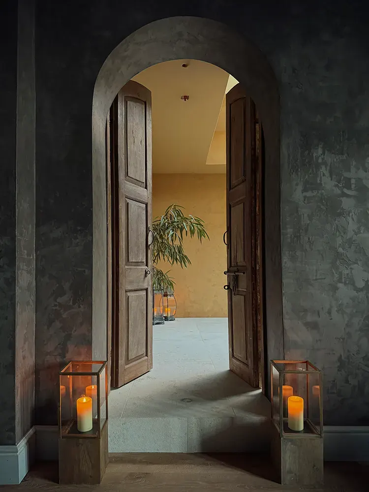 Arched wooden doors into a treatment room, lit by lanterns