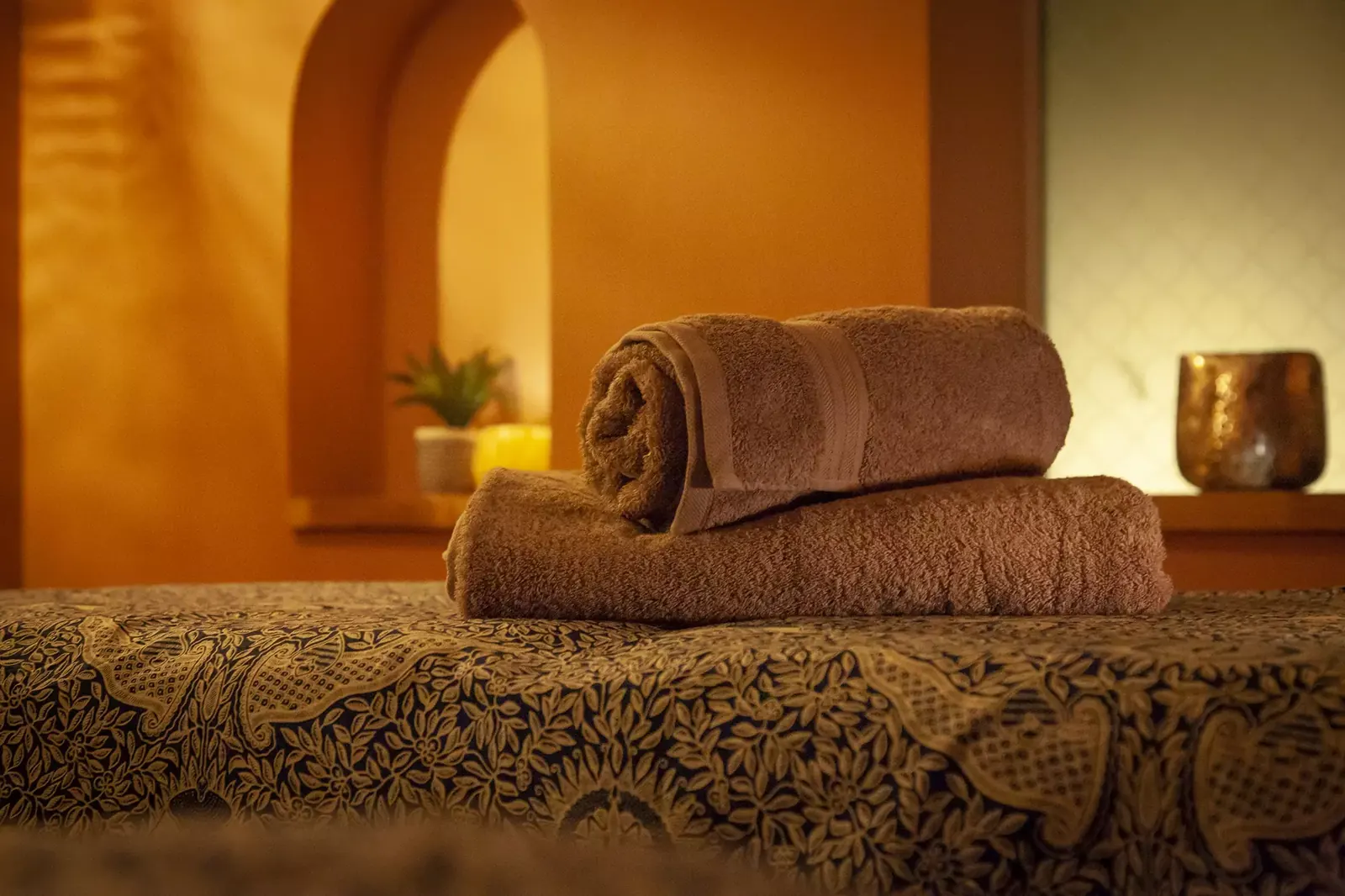 Rolled towels on a treatment bed in warm light