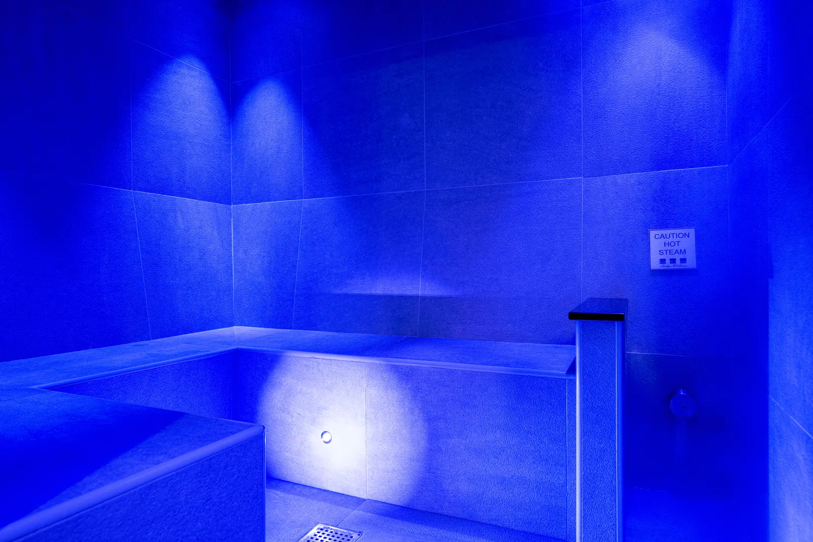 Blue-lit steam room with tiled bench