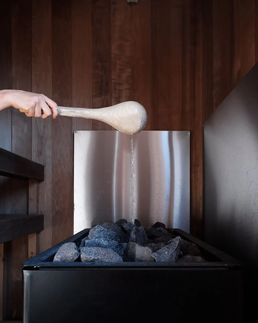 Ladling water onto the sauna stones during an aufguss