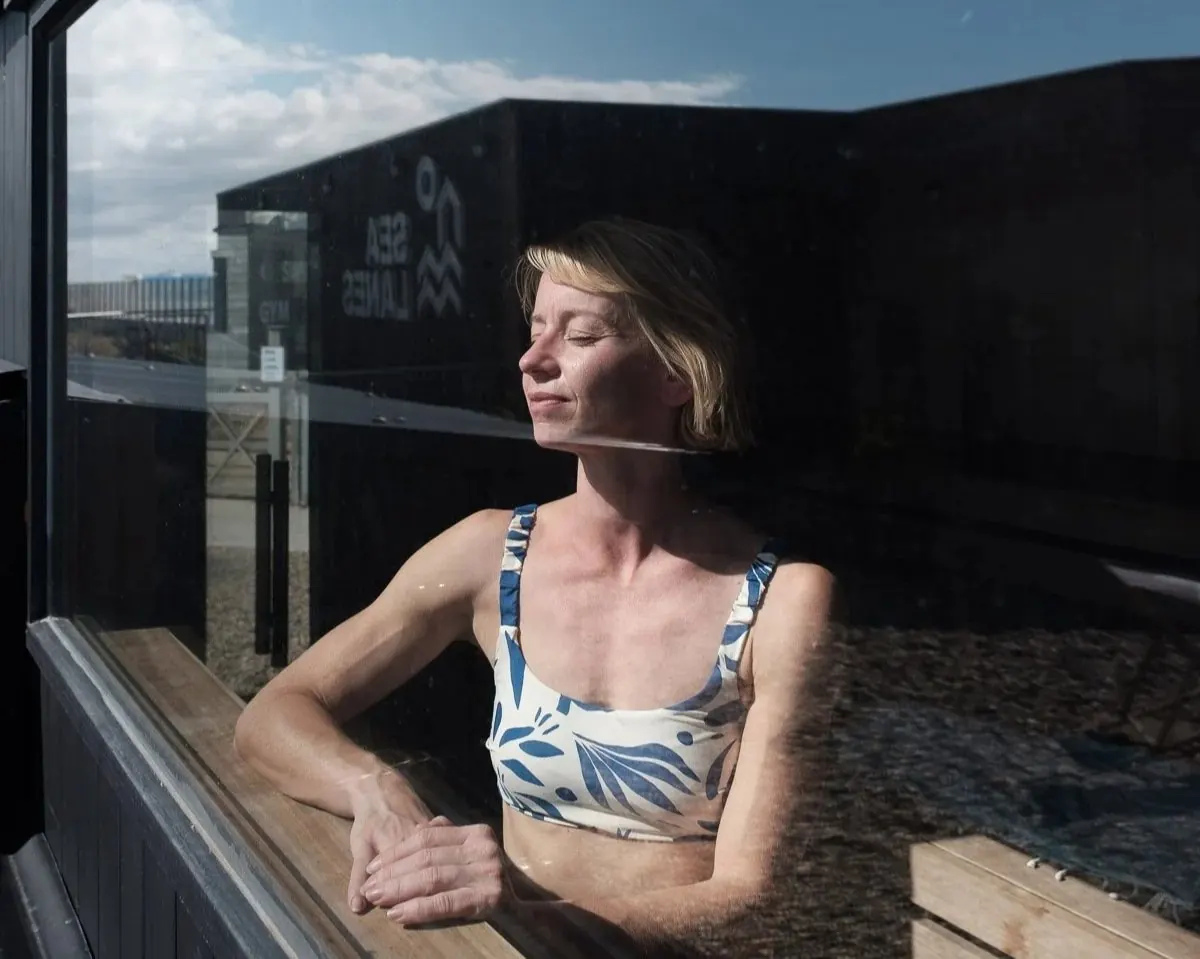 Woman relaxing behind the sauna window, sun on her face