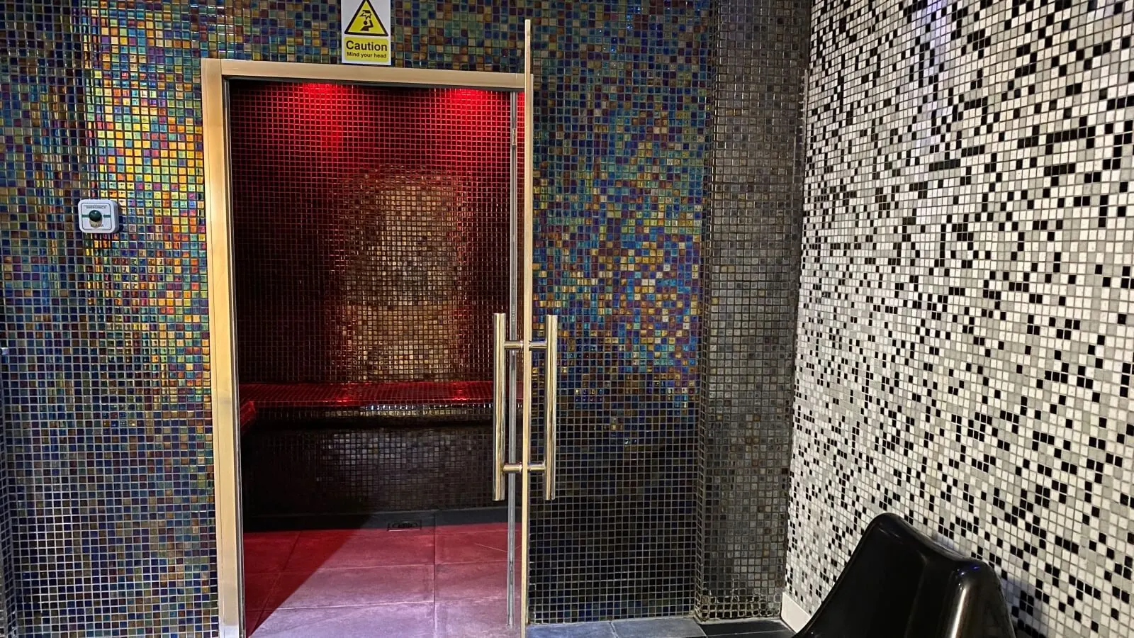 Mosaic-tiled steam room with glass door