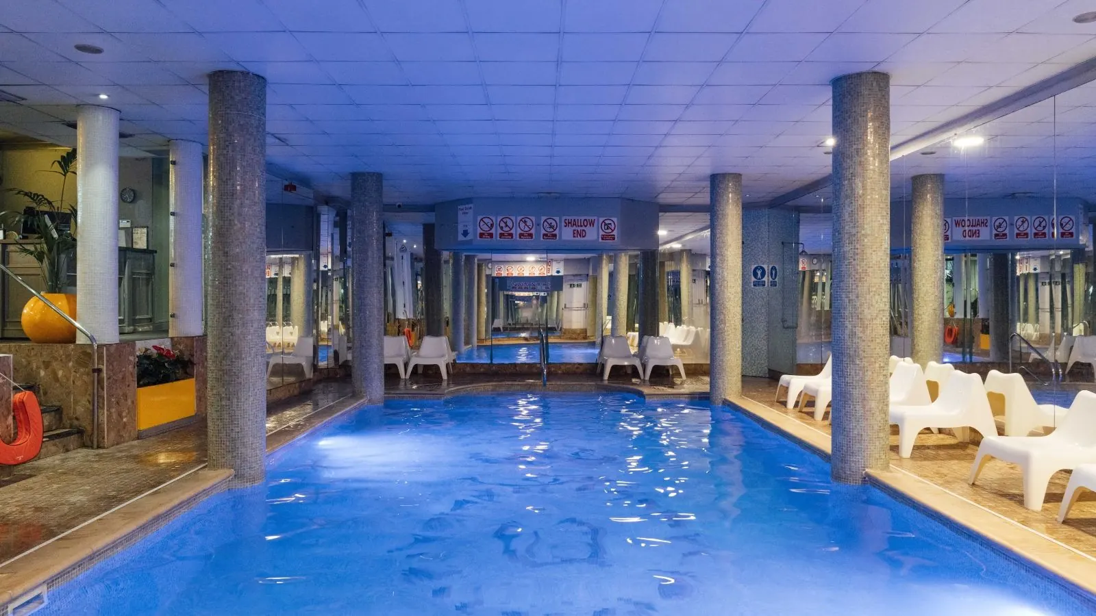 Indoor pool with columns and white loungers