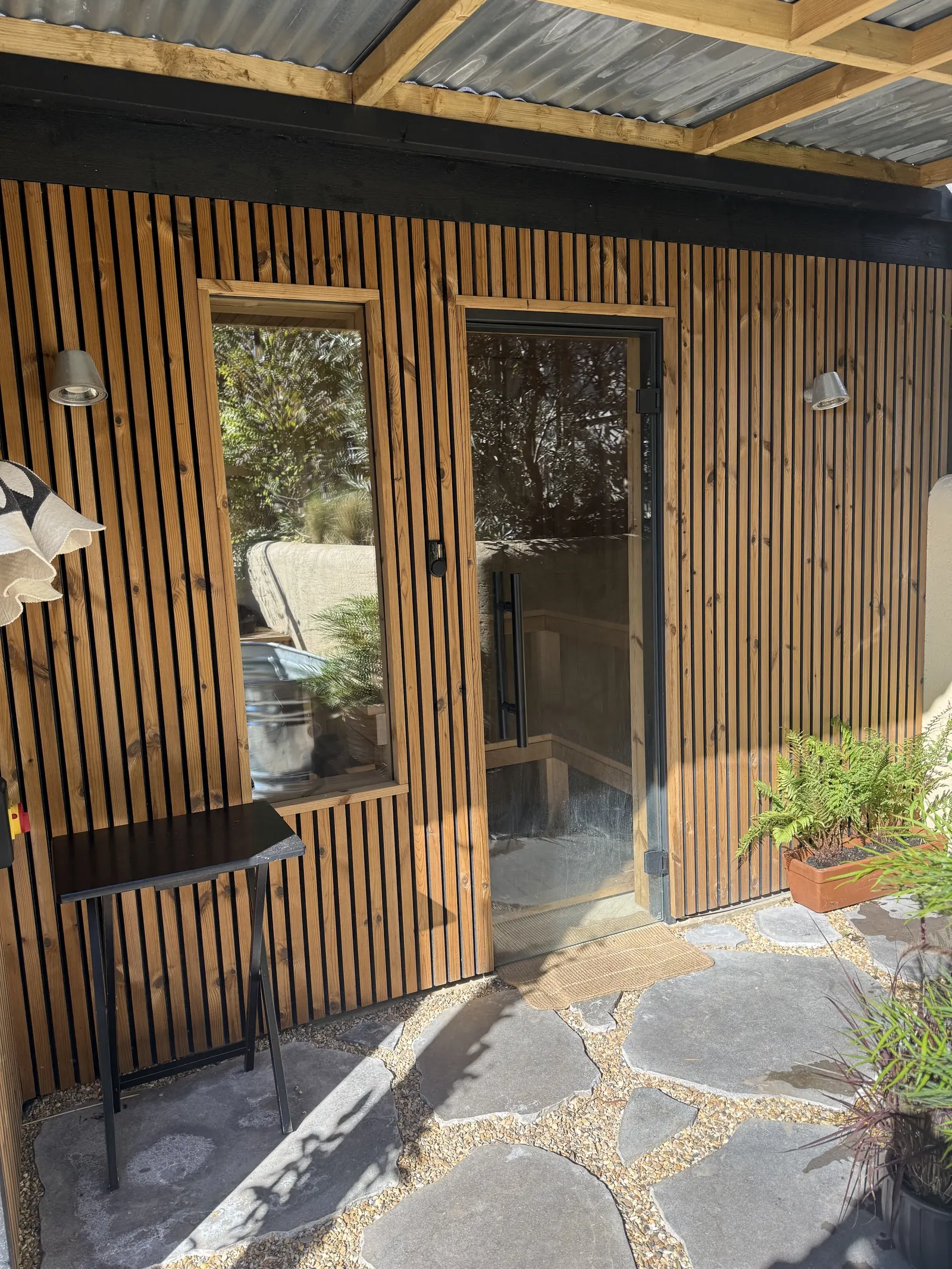 Slatted-wood sauna exterior and stone patio
