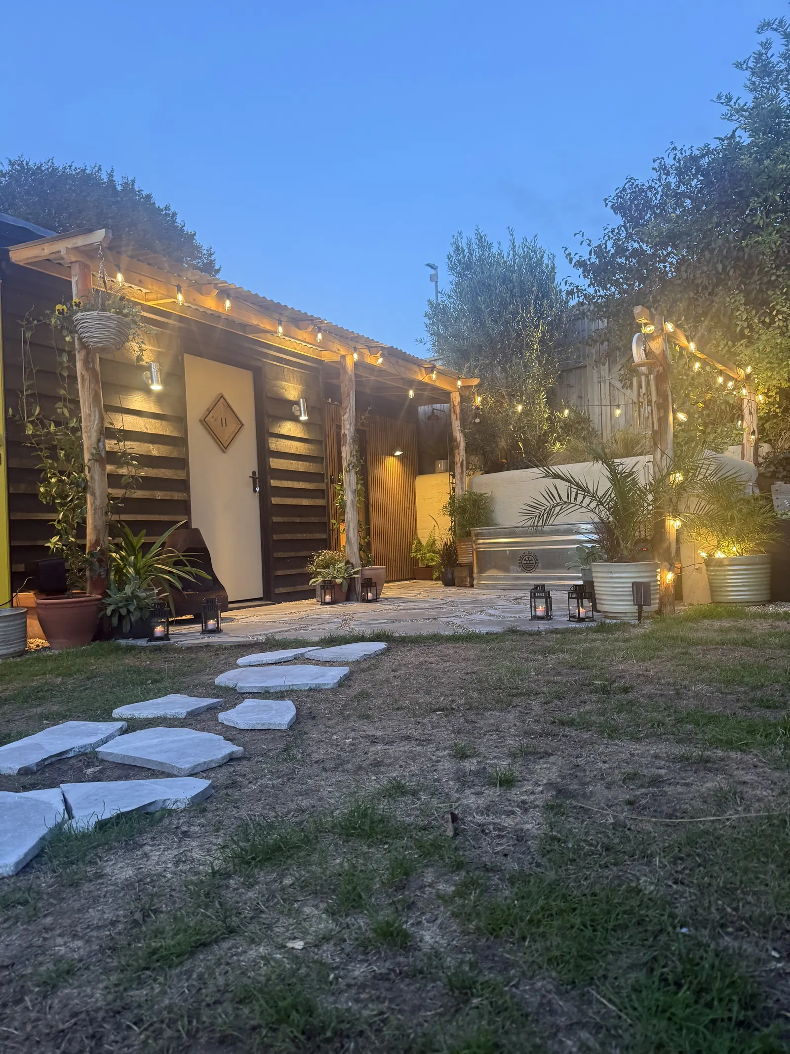 The sauna yard at dusk, strung with fairy lights